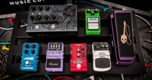 Deretan distortion pedal metal di atas papan pedal gitar dengan kabel terhubung